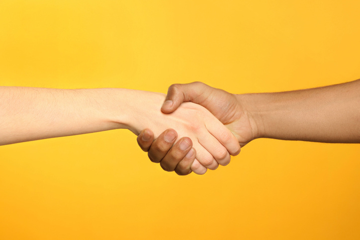 closeup of People shaking hands on yellow background.