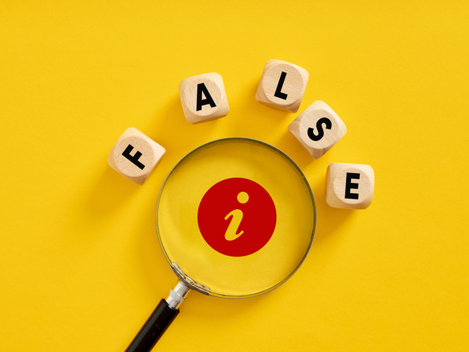 The word false on wooden cubes with a magnifier against a yellow background