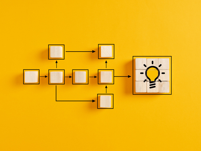 Wooden cubes representing idea generation with light bulb icon on yellow background