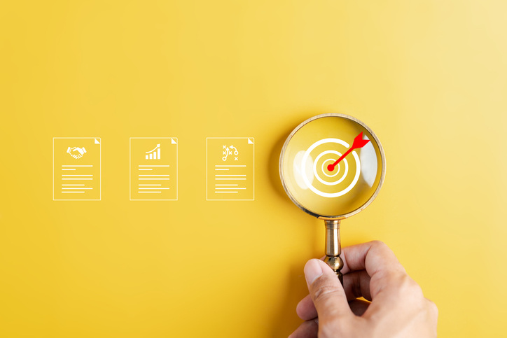 Magnifying glass with target goal and document icons on yellow background